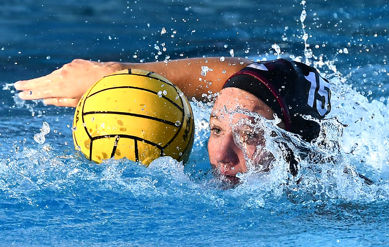Woman waterpolo swimmer swimming next to ball.